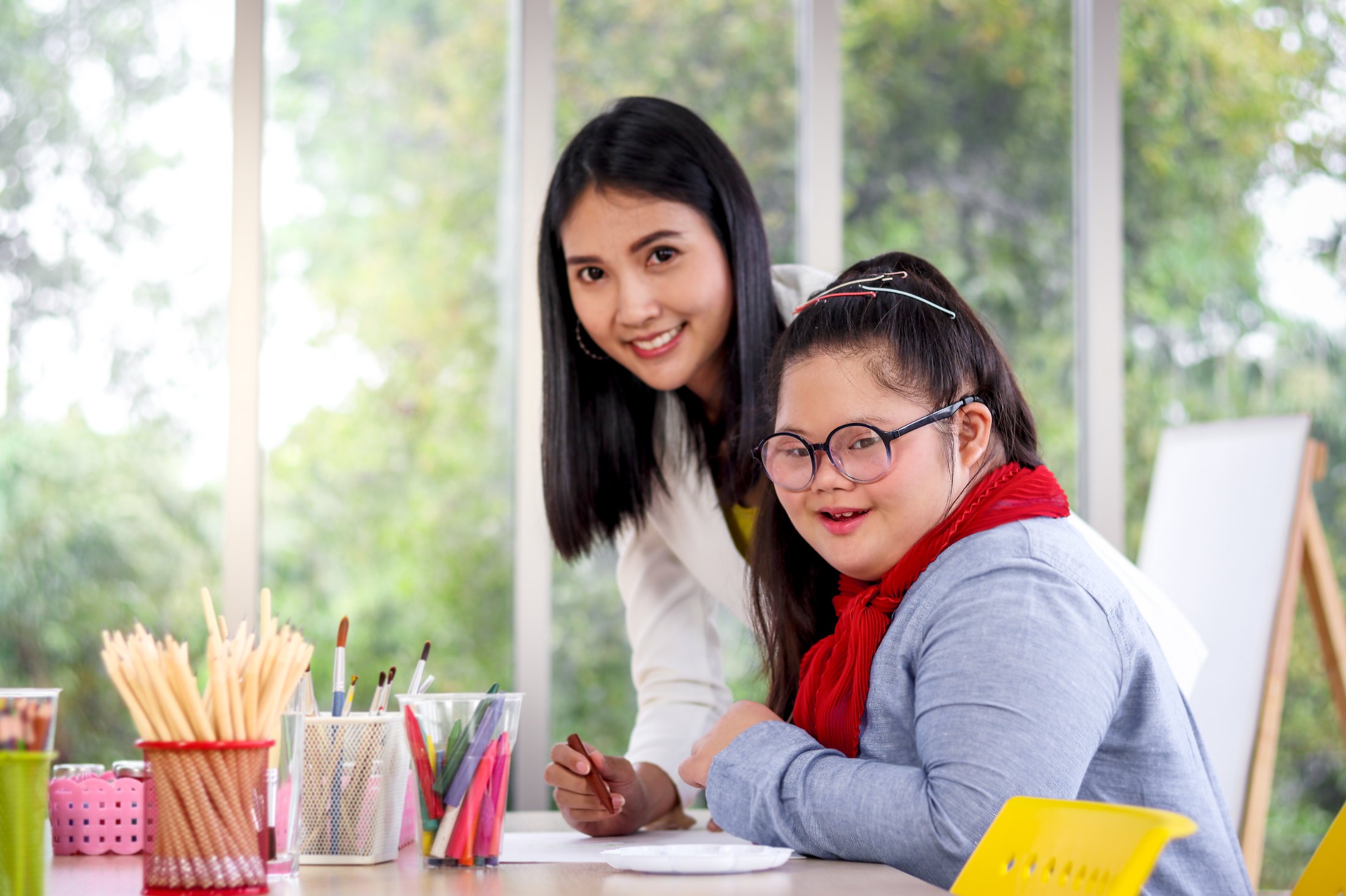A support worker with a young woman doing an art activity